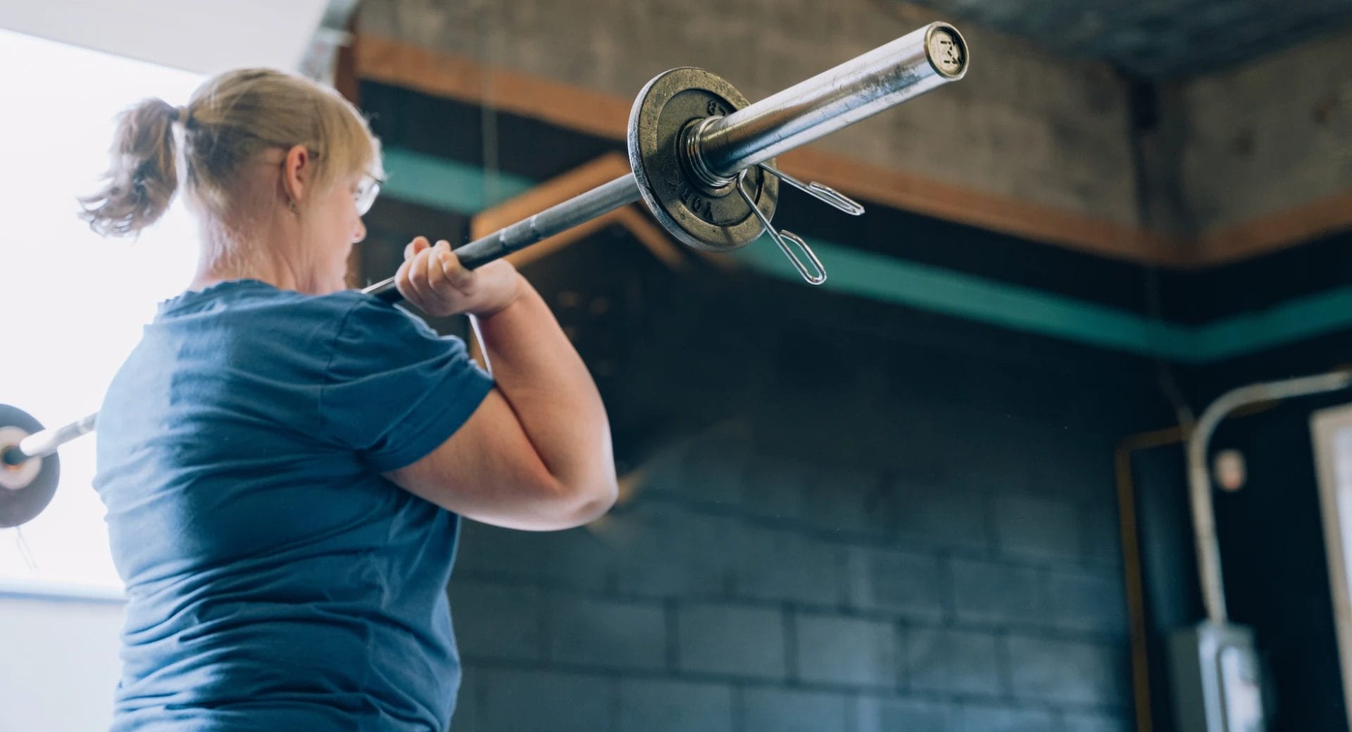 Member training barbell clean movement at CrossFit Fortis strength and conditioning gym